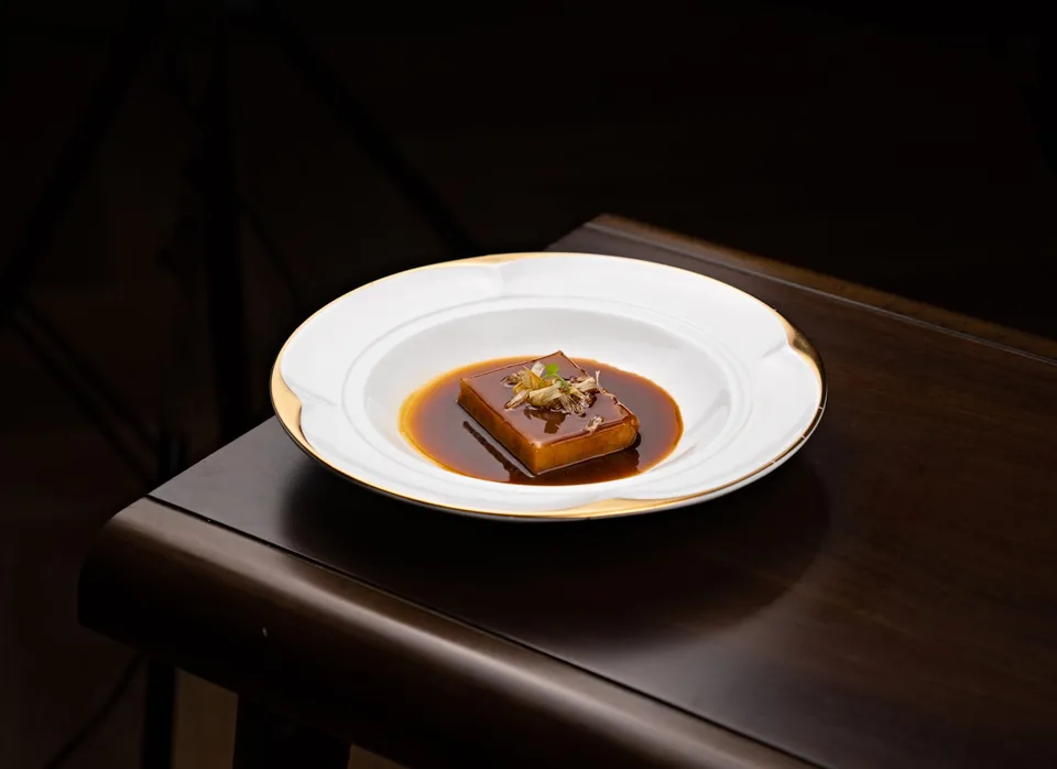 A caramel custard in a white bowl on a dark wooden table